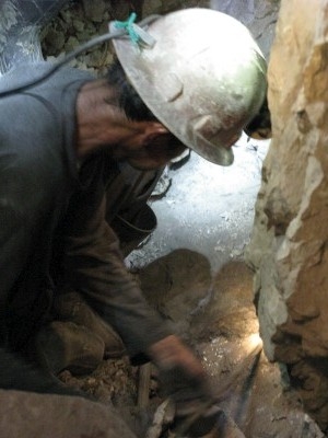 Miner drilling hole by hand for a dynamite charge Miner drilling hole by hand for a dynamite charge